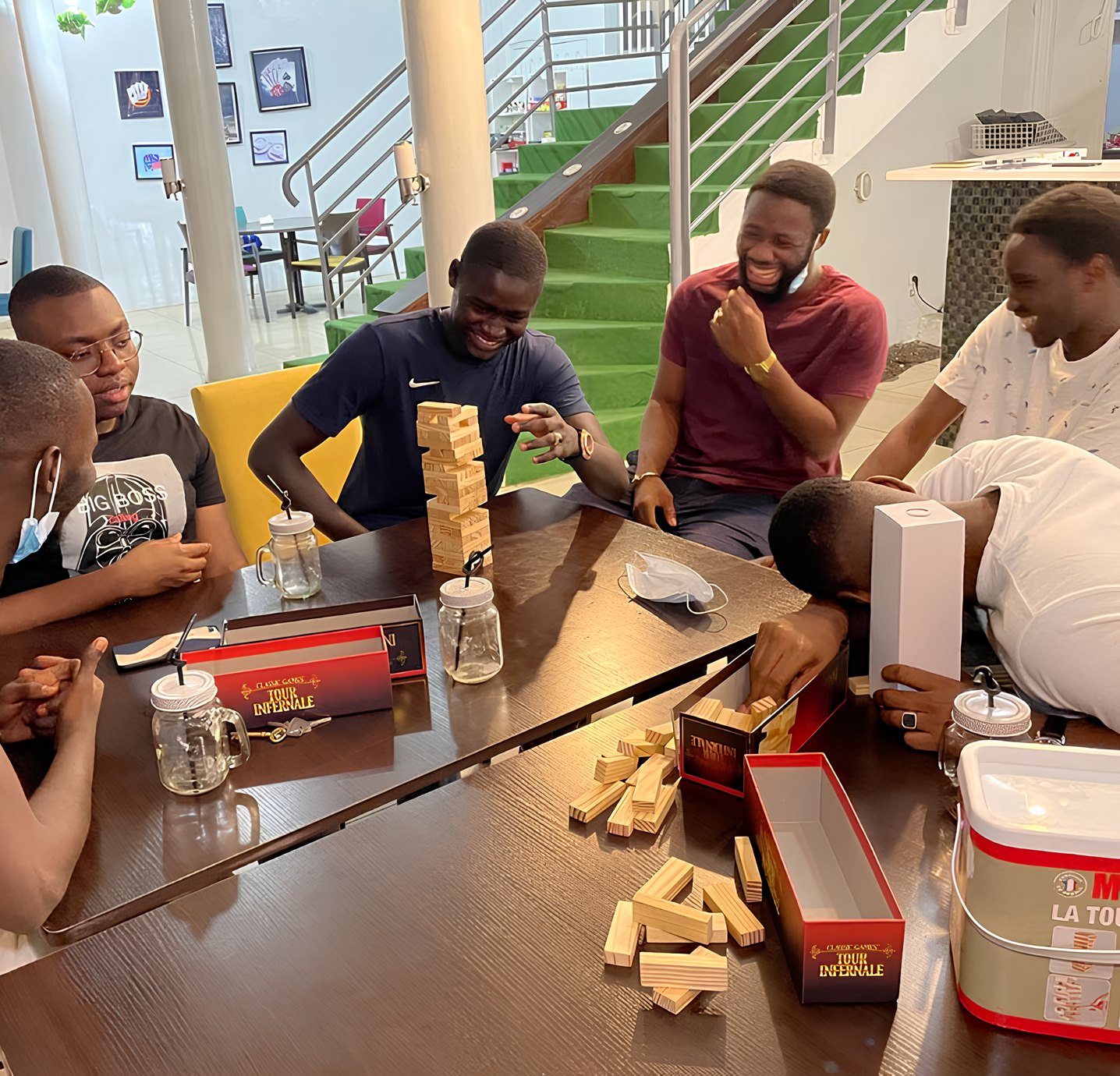 Collègues jouant à Jenga pendant un afterwork à Dakar, s'amusant en intérieur.