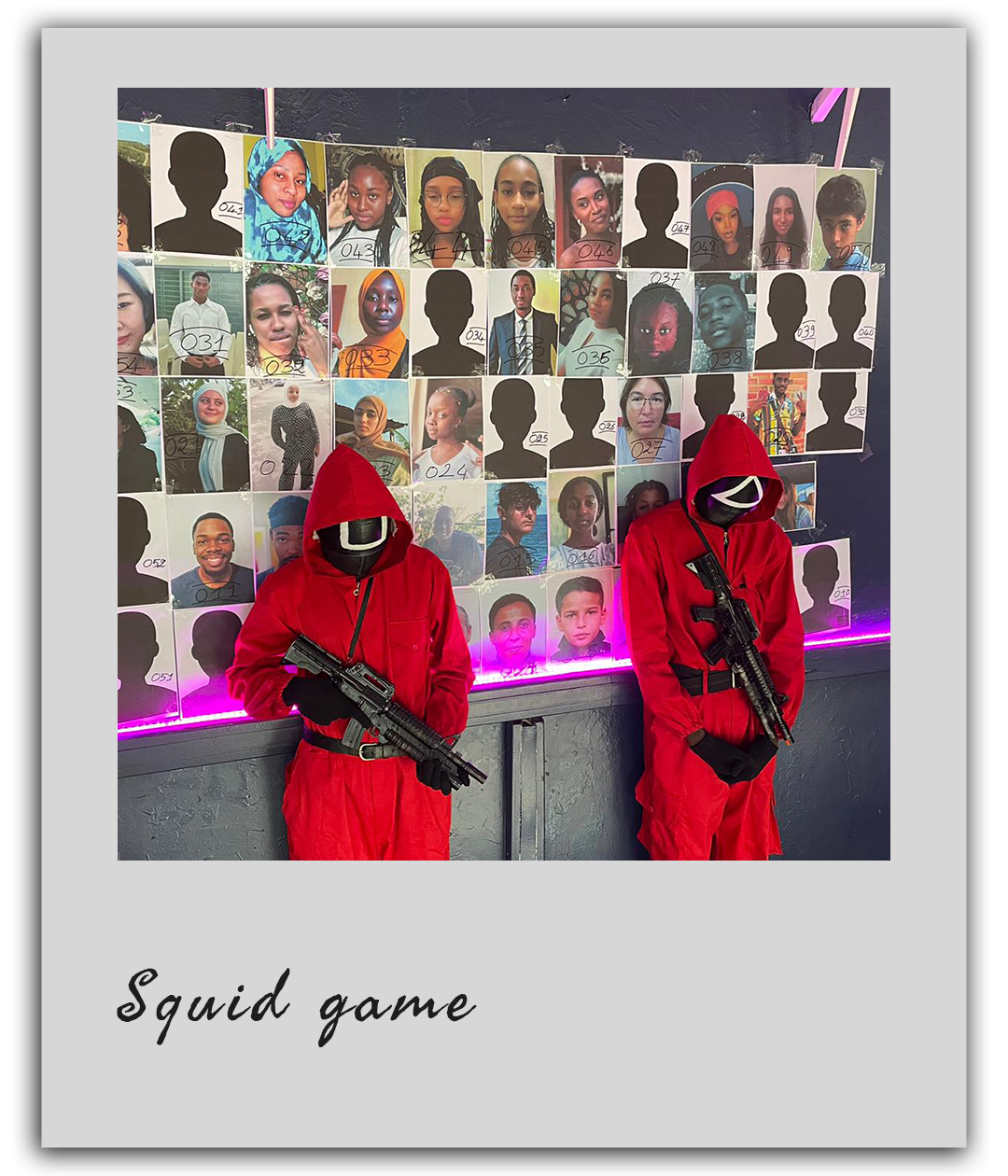 Deux participants déguisés en gardes rouges de Squid Game posent devant un mur de portraits pendant un team building à Dakar.