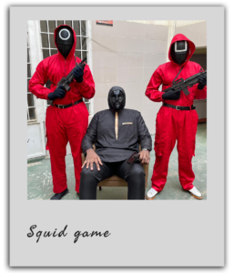 Un maître du jeu entouré de deux gardes rouges pose lors d’un team building Squid Game à Dakar.