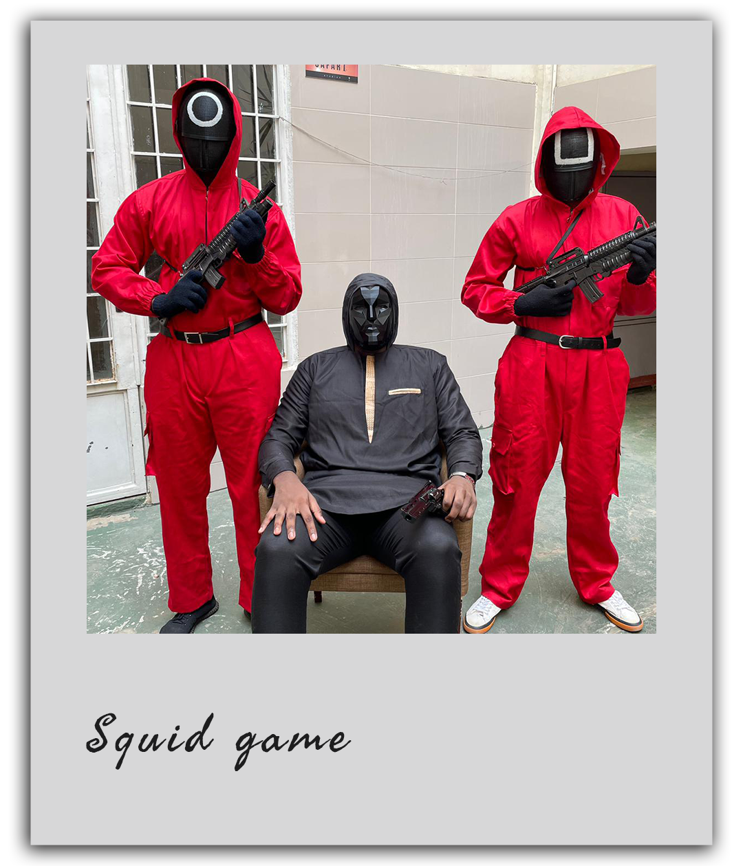 Un maître du jeu entouré de deux gardes rouges pose lors d’un team building Squid Game à Dakar.